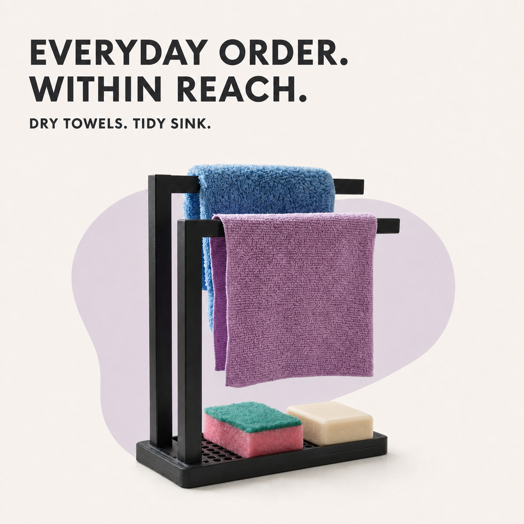 A black metal double-towel rack with a bottom shelf holding two cleaning sponges, shown with two towels draped over the bars. The image includes marketing text at the top: 'EVERYDAY ORDER.