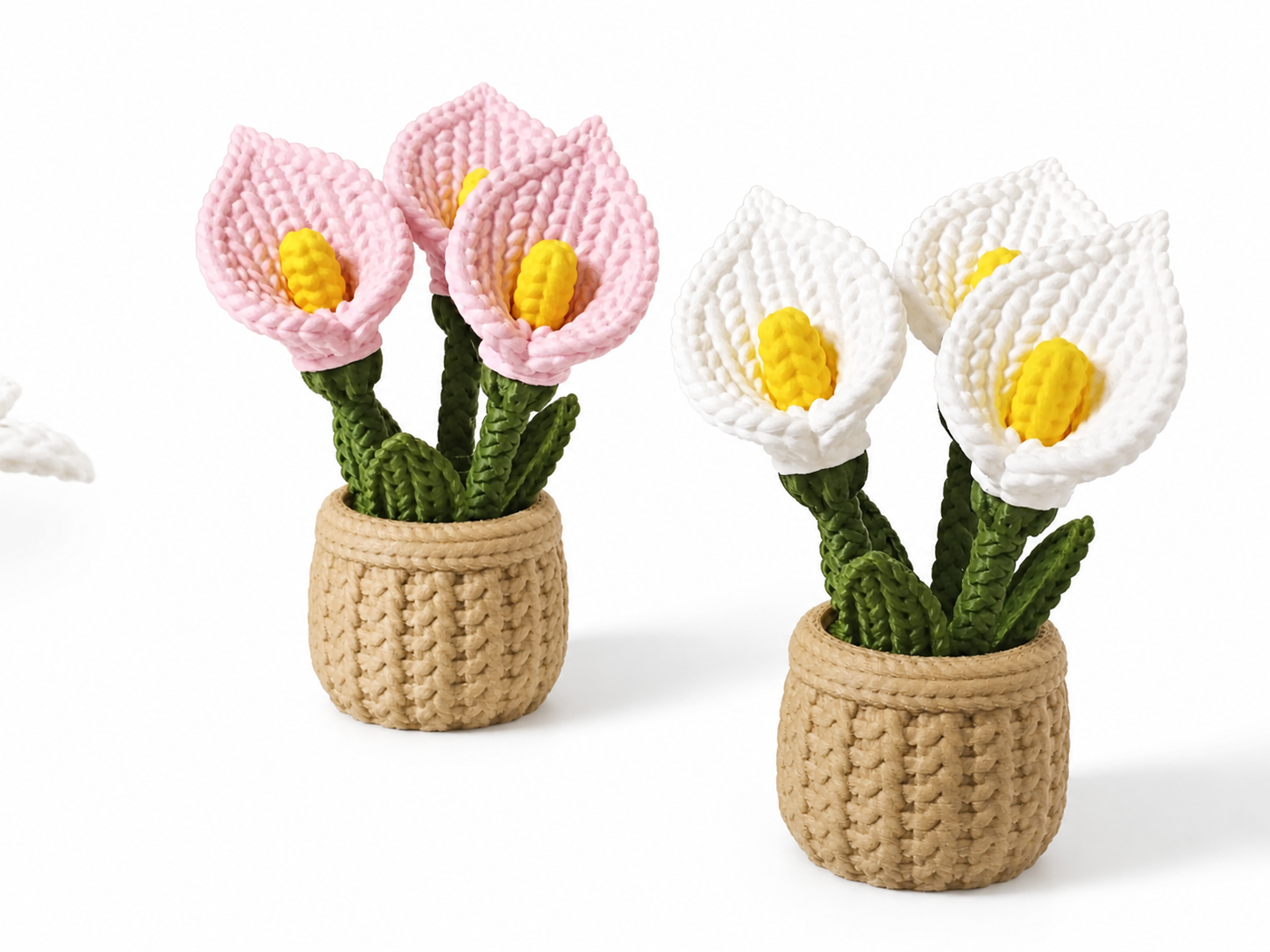 Two crocheted calla lily plant arrangements in beige woven pots, one with pink flowers and one with white flowers, both with yellow centers and green stems, on a white background.