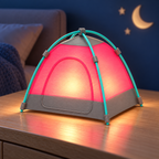A miniature dome-shaped camping lantern lamp shaped like a tent, featuring a glowing pink-red fabric body, gray base panels, and teal support poles, displayed on a wooden nightstand in a cozy bedroom setting.
