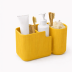 Yellow bathroom caddy with toiletries including a toothbrush, toothpaste, and soap on a white background